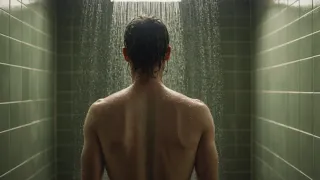 Cheveux longs mouillés vus de dos sous une douche à l'italienne, vapeur légère et carrelage vert d'eau en arrière-plan